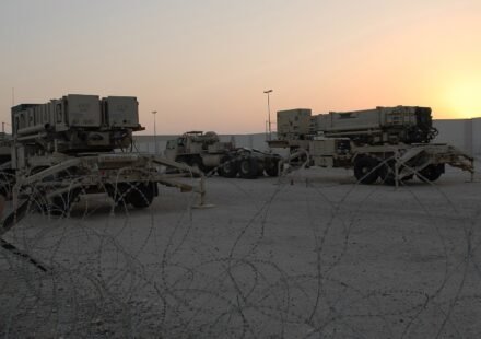Two Patriot PAC-3 missile launchers positioned at a military air base.