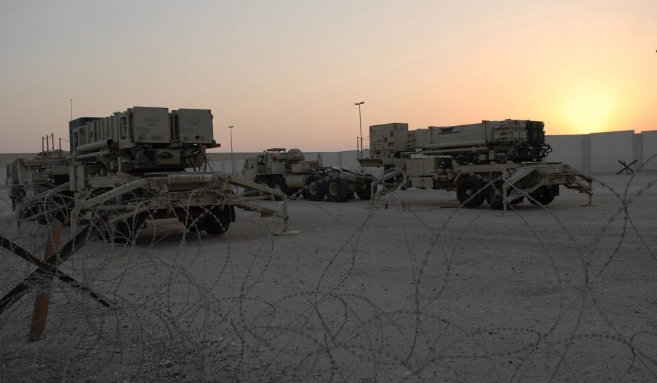 Two Patriot PAC-3 missile launchers positioned at a military air base.