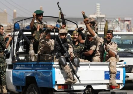Armed Houthi fighters carrying rifles and an RPG launcher in the back of a pickup truck in Yemen.