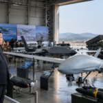 North Korean leader inspecting military drones at an exhibition as a missile launches in the background.